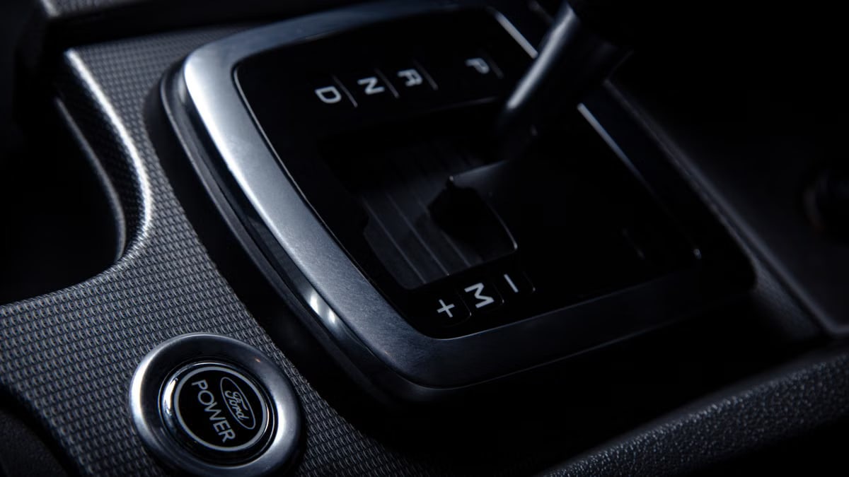 Detailed view of a car gear stick and push button in a modern vehicle interior.